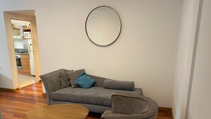 Een woonkamer met een grijze bank, een ronde salontafel en een grijze fauteuil.
