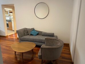 A living room with a grey sofa, a round coffee table, and a grey armchair.