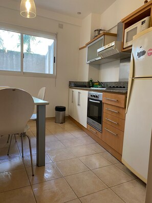 A kitchen with a dining table, cabinets, a stove, and a refrigerator.
