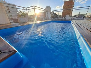 A rooftop swimming pool with a view of the city skyline.