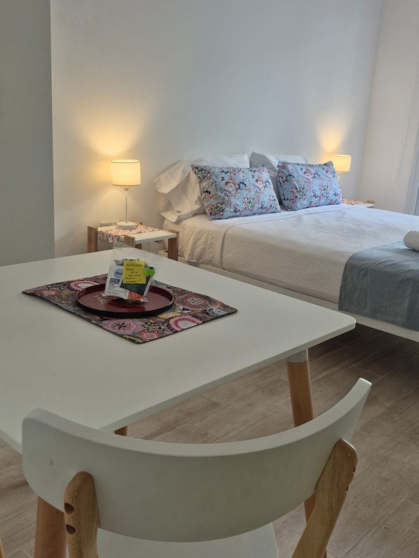 A hotel room with a bed, bedside lamps, a dining table with a placemat, and a chair.