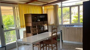 A kitchen with a white countertop, wooden chairs, a stove, and a window with yellow curtains. - Near the sea central location, attic 3 floor elevator climate. (San Benedetto del Tronto)