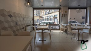 A modern cafe with geometric wall patterns, multiple seating areas, and a view of parked cars outside. - Hotiday Firenze Guidoni (Florence)