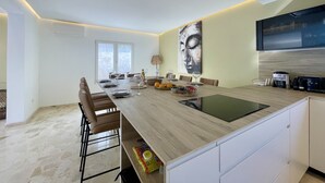 Une cuisine moderne dotée d’un îlot central, d’un coin repas avec des chaises et d’une grande fenêtre.