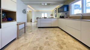 Une cuisine moderne avec des meubles blancs, un îlot central et une grande fenêtre.
