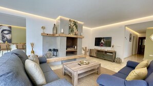 Un salon moderne avec une cheminée, un téléviseur et des sièges confortables.