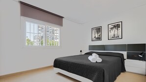 A modern bedroom with a bed, a nightstand, a lamp, and two framed pictures on the wall.