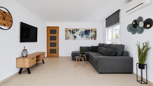 A modern living room with a grey sofa, wooden sideboard, and a flat-screen TV.