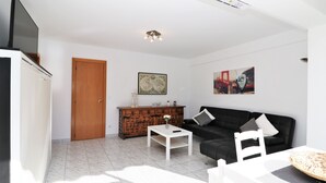 Una sala de estar moderna con un sofá negro, una mesa de centro blanca y un mueble de madera.