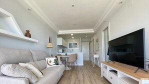 Uma sala de estar moderna com um sofá cinzento, uma televisão de tela plana e uma mesa de centro de madeira.