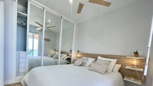 Quarto com uma cama grande, guarda-roupa com portas deslizantes, ventilador de teto, abajures e mesa de cabeceira.
