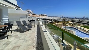 Una terraza en la azotea con mobiliario exterior, una piscina y vistas a la ciudad.