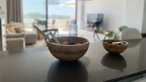 Una sala de estar moderna con un ventanal grande, una mesa de comedor con un cuenco de madera y una lámpara colgante.