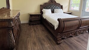 Un dormitorio con una cama de madera grande, un aparador y un espejo.