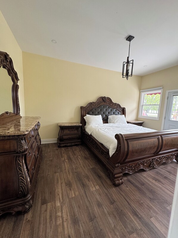 A bedroom with a large wooden bed, a dresser, and a mirror.