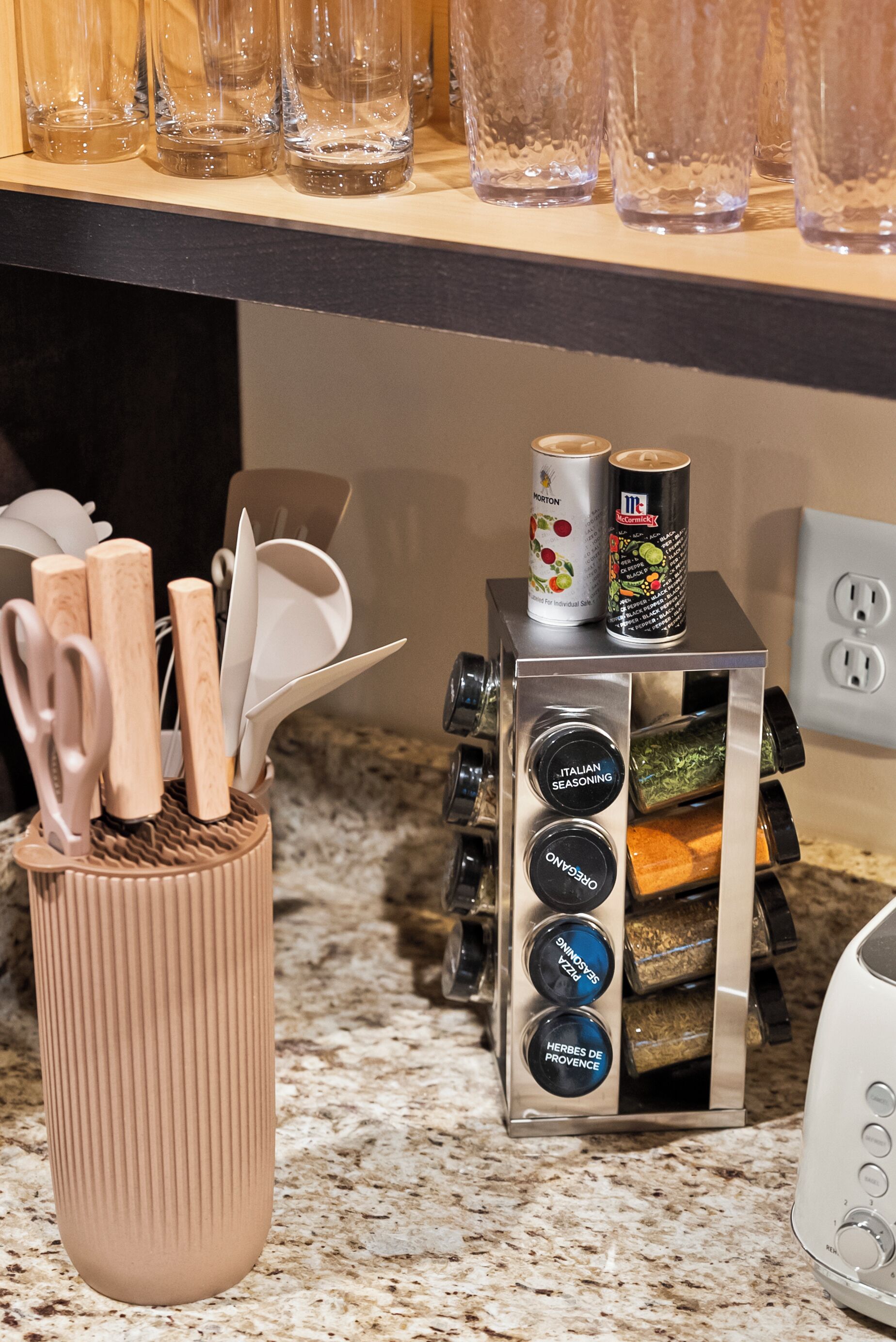 A kitchen counter with a spice rack, a can of Morton's seasoning, and a can of McCormick spices.