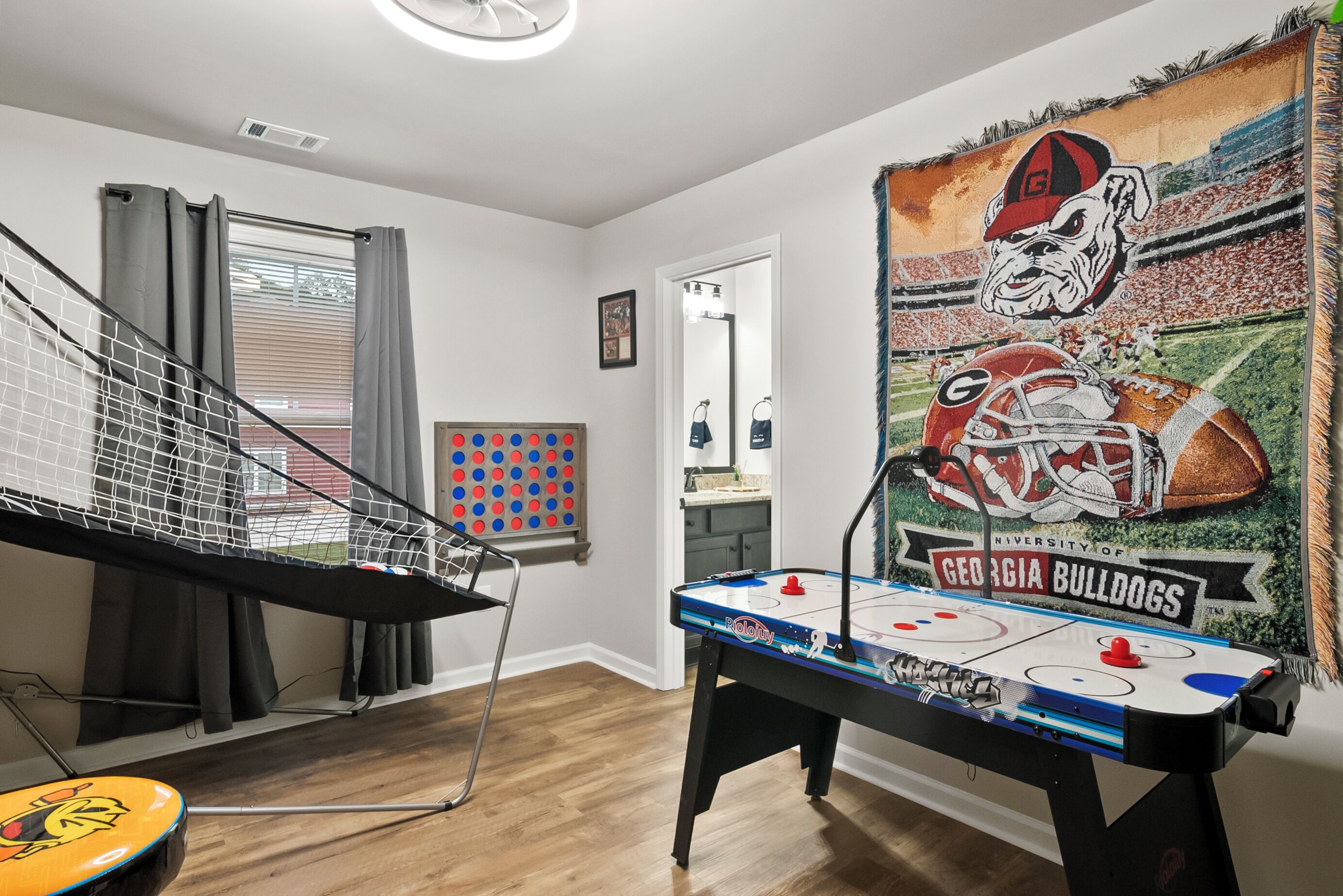 A room with a foosball table, a hockey table, and a mural of Georgia Bulldogs.