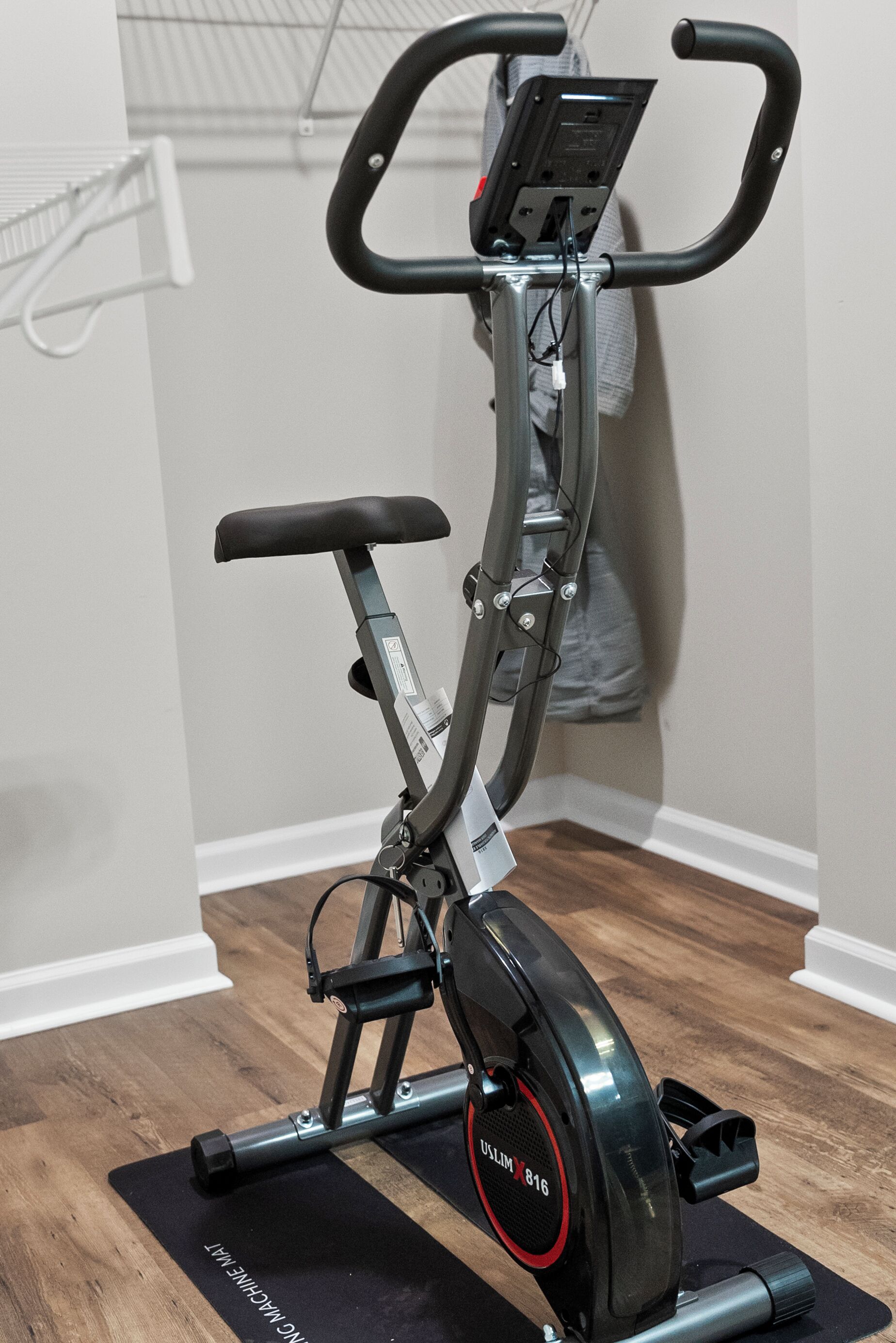 A stationary bike in a room with wooden flooring and white walls.