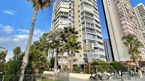 A tall residential building with multiple balconies and a palm tree in the foreground. - TORRE YAGO SEAFRONT LEVANTE N028 (Benidorm)
