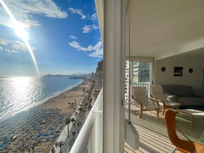 Een balkon met uitzicht op een strand en een stadshemelbeeld.