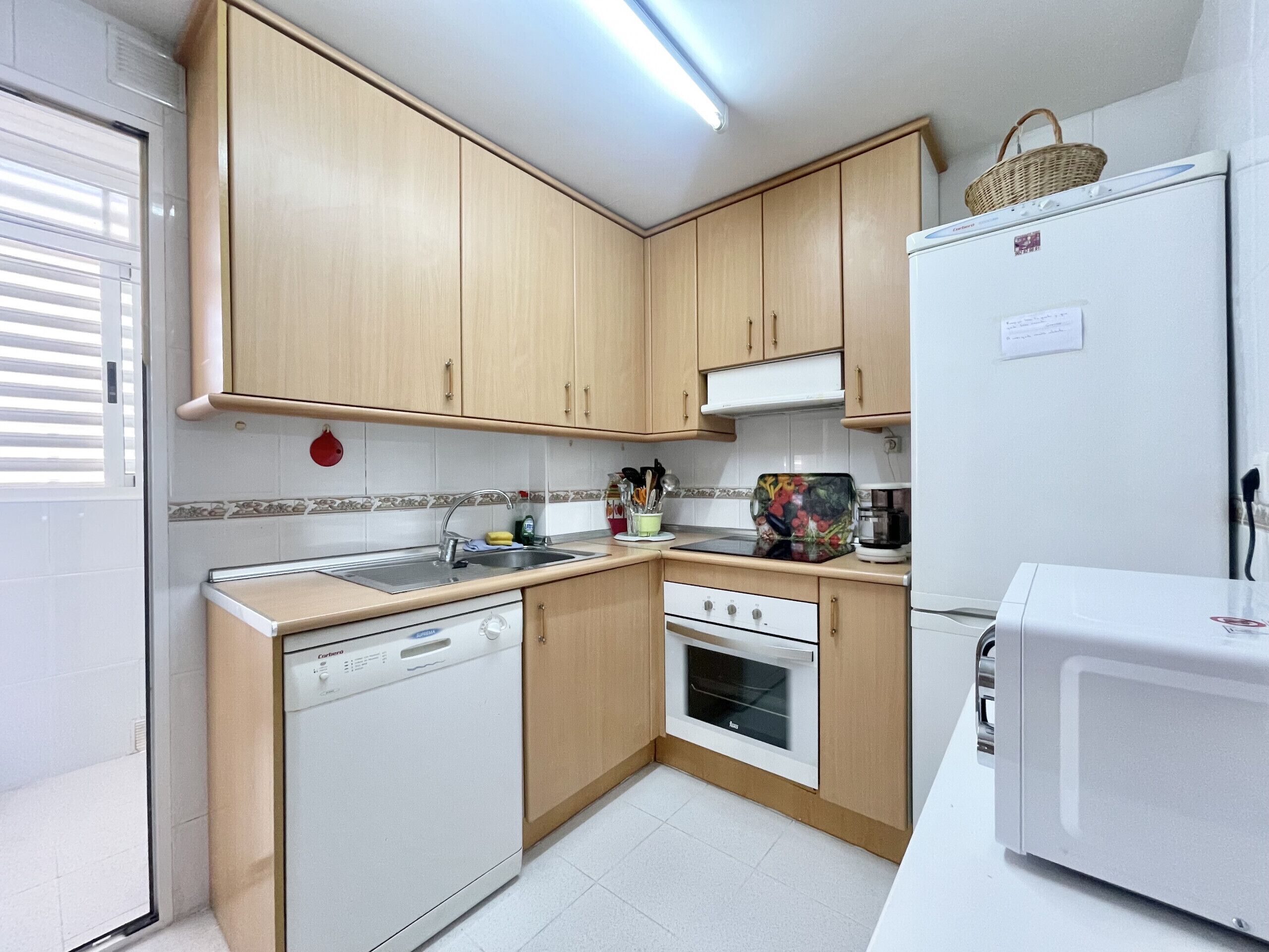 A compact kitchen with wooden cabinets, a dishwasher, an oven, and a refrigerator.