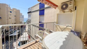 A balcony with a tiled table, a white chair, and a red awning.