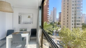 A balcony with a dining area, a large mirror, and a view of tall buildings and trees. - PARAISO LEVANTE BEACH STUDIO N105 (Benidorm)