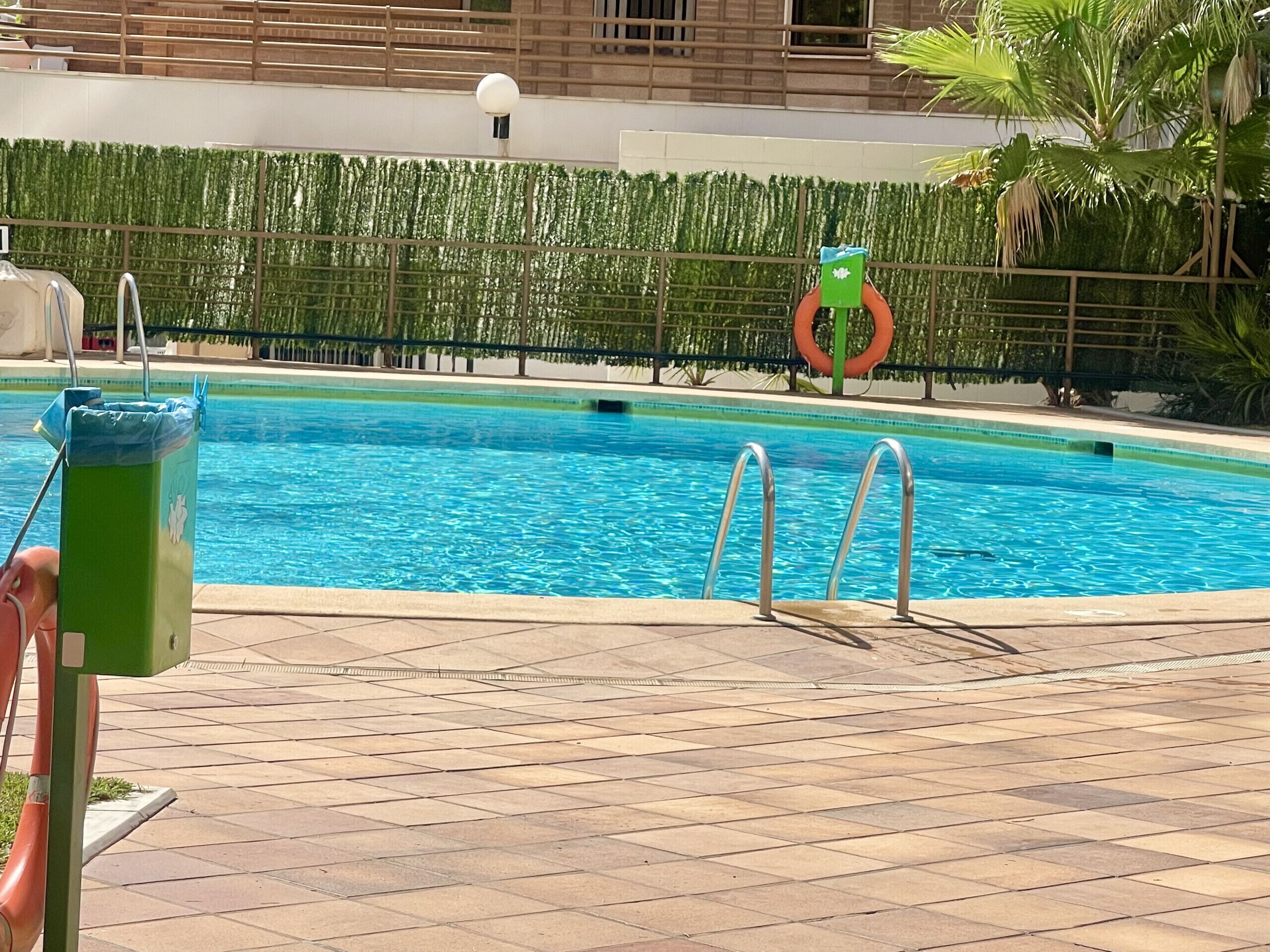 A swimming pool with clear blue water, surrounded by a tiled deck.