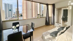 A modern hotel room with a large window, a glass table, and a sofa. - NEW TOWN LEVANTE BEACH (N121) (Benidorm)