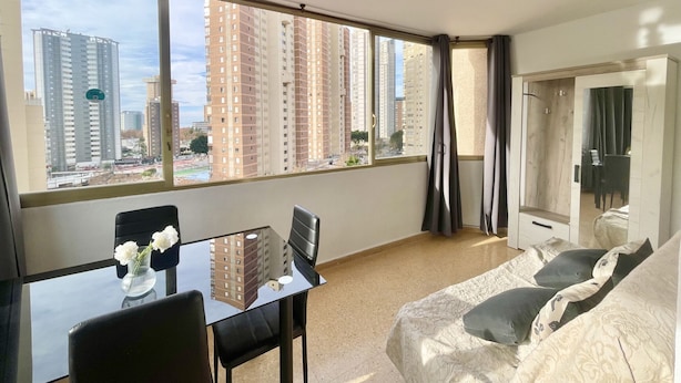 A modern hotel room with a large window, a glass table, and a sofa. - NEW TOWN LEVANTE BEACH (N121) (Benidorm)
