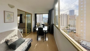 A modern hotel room with a balcony, a dining area, and a view of the cityscape. - NEW TOWN LEVANTE BEACH (N121) (Benidorm)