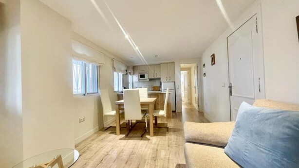 Een ruimtelijk ingerichte leefruimte met kitchenette, eethoek en zithoek.