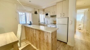 Een kleine keuken met een houten kookeiland, witte keukenkastjes en een ingebouwde magnetron.