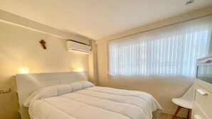 Een slaapkamer met een bed, nachtkastje en een raam met gordijnen.