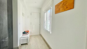 Ein Flur mit einer weißen Tür, einem Fenster und einem Wandbild.