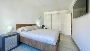 Ein Schlafzimmer mit einem Bett, einem Nachttisch mit Lampe, einem Sessel und einem Kleiderschrank.