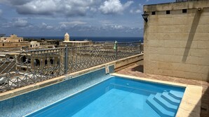 A rooftop swimming pool with a view of the sea and cityscape.