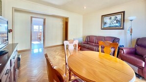 Una sala de estar con una mesa de comedor de madera, dos sofás y un televisor.