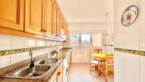 Una cocina con armarios de madera, encimera de granito, un lavamanos y una zona de comedor con mesa y sillas.