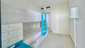 A bedroom with a bunk bed, a desk, a wardrobe, and a door leading to another room. - MIRADOR DEL MEDITERRANEO N172 (Benidorm)