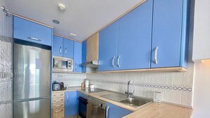A modern kitchen with blue cabinets, stainless steel appliances, and a wooden countertop. - MIRADOR DEL MEDITERRANEO N172 (Benidorm)