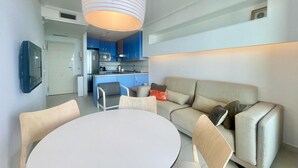 A modern living room with a round white table, beige sofa, and a kitchen in the background. - MIRADOR DEL MEDITERRANEO N172 (Benidorm)