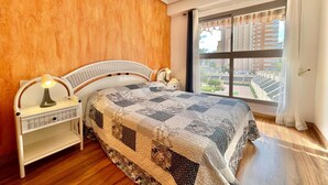 Un dormitorio con una cama grande, dos lámparas de noche, una mesita de noche y una ventana con vistas a edificios.