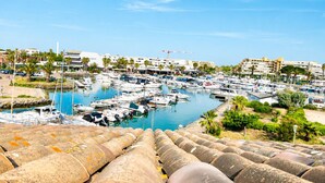 A marina with numerous boats docked, surrounded by buildings and palm trees. - Naturiste Cap d'Agde Port Soleil 146 (Agde)