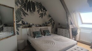 A bedroom with a bed, a dresser, a mirror, and a window with curtains.