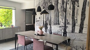 A dining area with a table, chairs, a vase, and a wall mural.