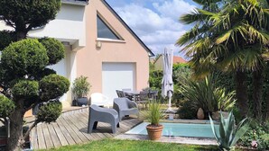 A modern house with a pool, patio furniture, and lush landscaping.