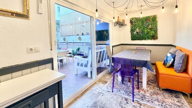 Eine moderne Küche mit Essbereich, einer eingebauten Sitzbank und Blick durch eine Glastür auf eine Terrassenfläche.