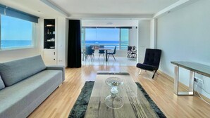 Una sala moderna con un sofá, una mesa de centro y vista al océano.