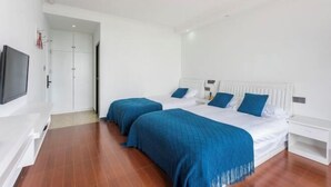 Un dormitorio con dos camas, un televisor y un armario blanco.